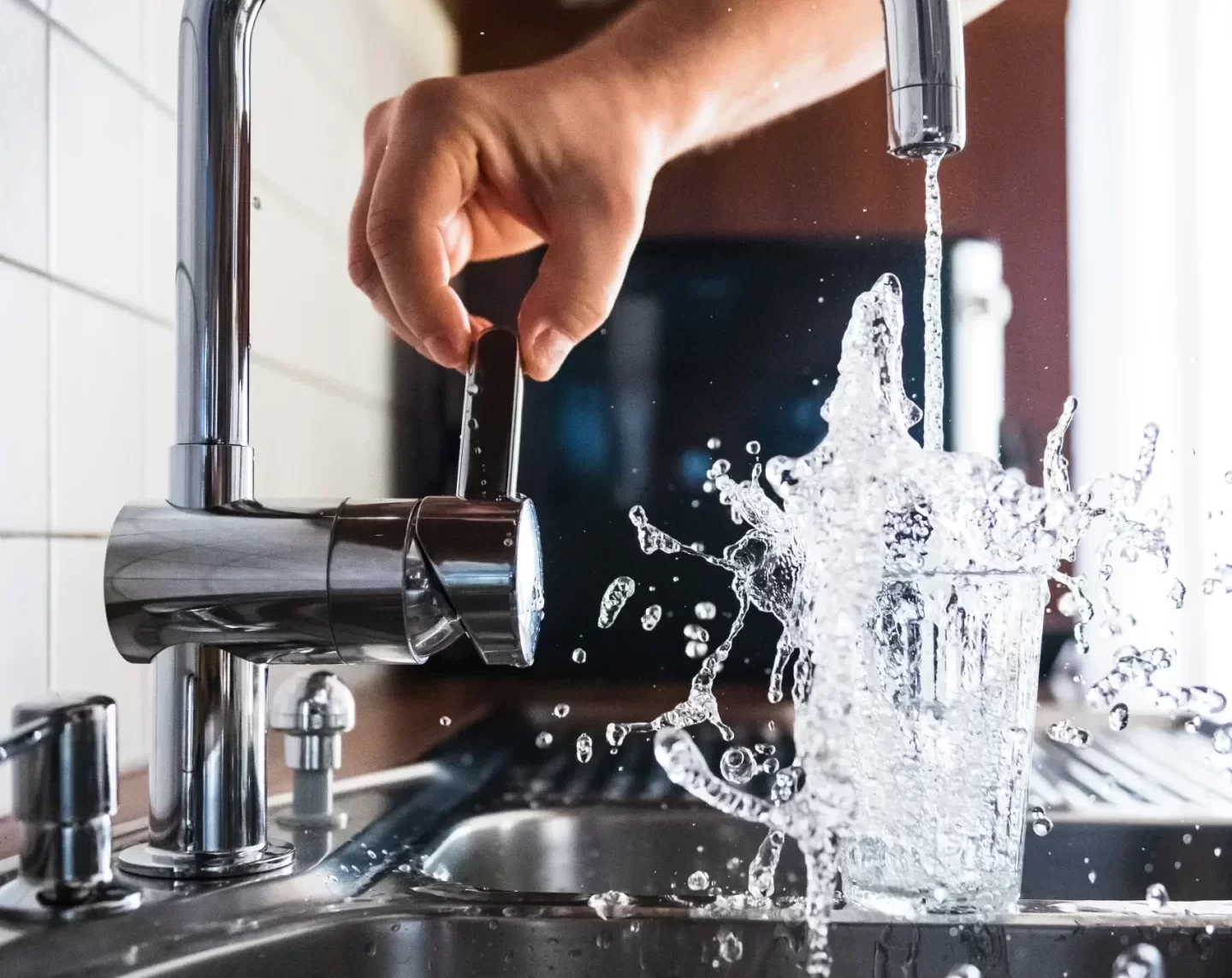kitchen-sink-water-splash-glass Water splashing out of glass under forceful faucet stream in modern kitchen sink.